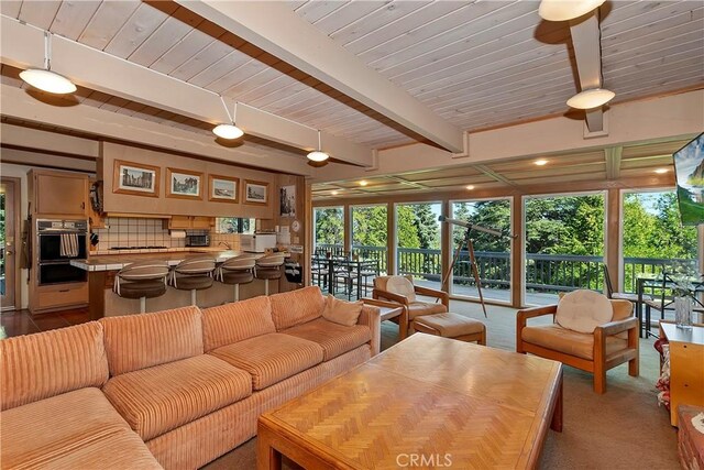 carpeted living room with beam ceiling