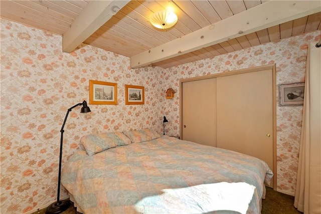 bedroom with beamed ceiling, a closet, and wood ceiling