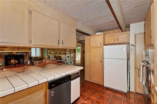 kitchen featuring beamed ceiling, tile counters, light brown cabinets, and appliances with stainless steel finishes