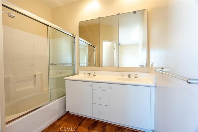 bathroom featuring hardwood / wood-style floors, vanity, and shower / bath combination with glass door