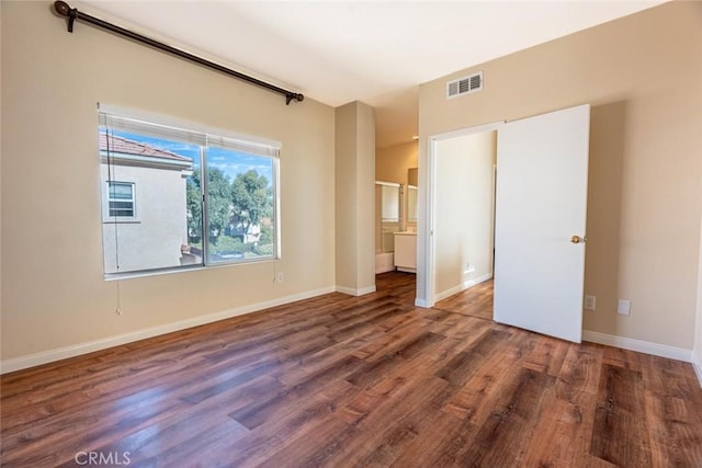 unfurnished bedroom featuring ensuite bath and dark wood-type flooring