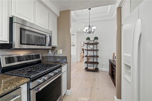 kitchen featuring white cabinets, a raised ceiling, light hardwood / wood-style flooring, stainless steel appliances, and a chandelier