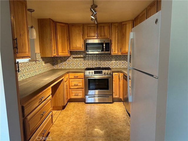 kitchen featuring pendant lighting, light tile patterned floors, rail lighting, appliances with stainless steel finishes, and backsplash