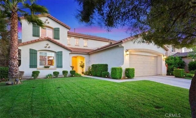 mediterranean / spanish-style house featuring a garage and a lawn