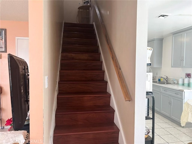 stairs with tile patterned floors and sink