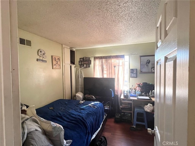 bedroom featuring a textured ceiling and dark hardwood / wood-style floors