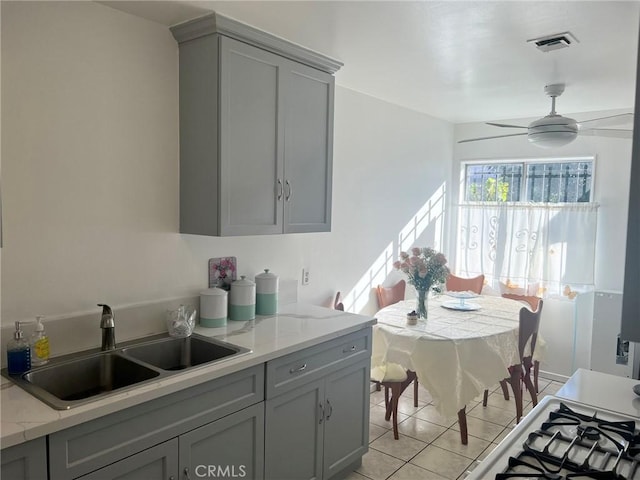 kitchen featuring gray cabinetry, light stone counters, sink, and ceiling fan