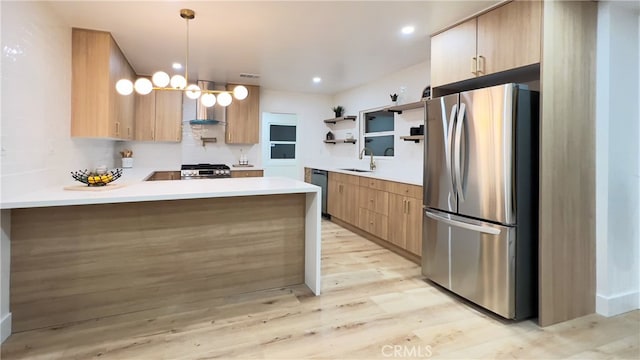 kitchen featuring sink, hanging light fixtures, light hardwood / wood-style flooring, appliances with stainless steel finishes, and kitchen peninsula