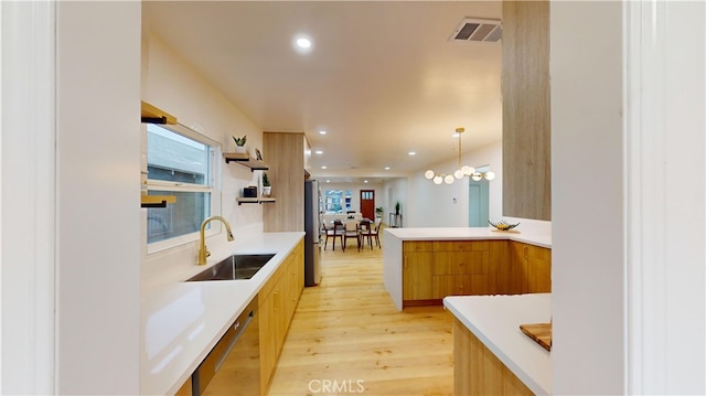 kitchen with stainless steel appliances, sink, pendant lighting, light hardwood / wood-style flooring, and a chandelier