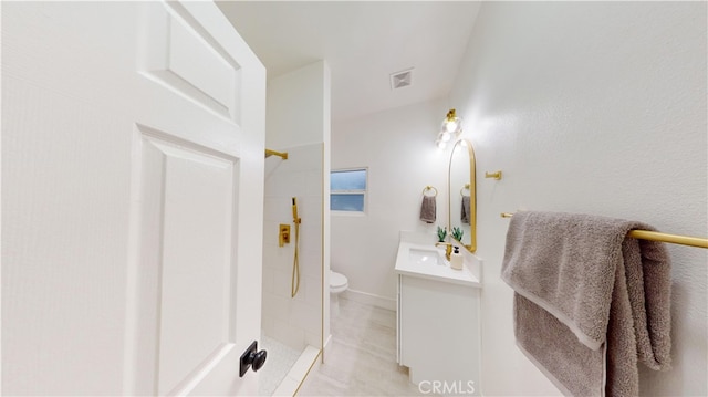 bathroom featuring tile patterned floors, toilet, vanity, and walk in shower