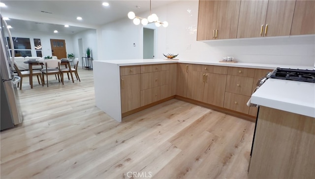 kitchen featuring kitchen peninsula, hanging light fixtures, and light hardwood / wood-style flooring