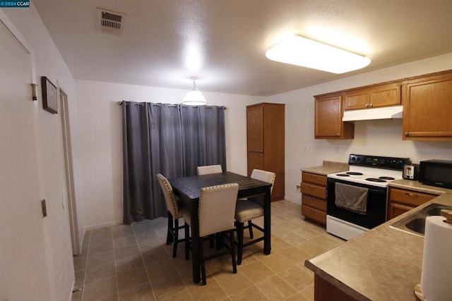 kitchen featuring pendant lighting, sink, electric stove, and a breakfast bar area