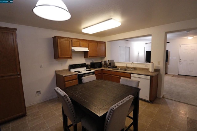 kitchen featuring dark tile patterned floors, white appliances, and sink