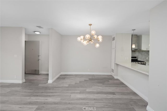 unfurnished dining area featuring light wood-type flooring and a notable chandelier