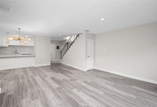 unfurnished living room featuring a chandelier and light hardwood / wood-style flooring