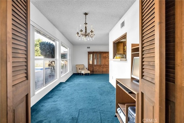 interior space with a chandelier, a textured ceiling, and dark colored carpet