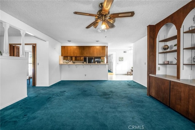 unfurnished living room with ceiling fan, a textured ceiling, and dark colored carpet