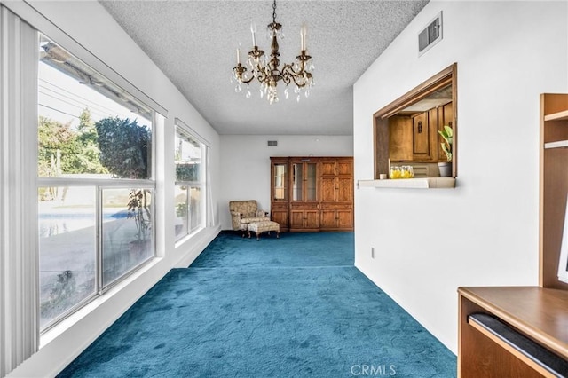 sitting room featuring dark carpet, a textured ceiling, and a chandelier