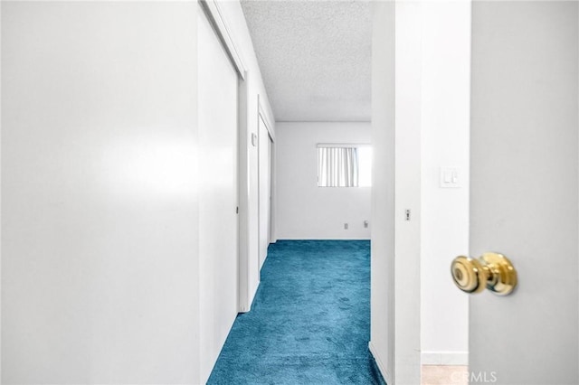 corridor featuring dark carpet and a textured ceiling