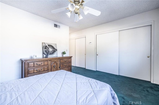 carpeted bedroom featuring two closets, ceiling fan, and a textured ceiling