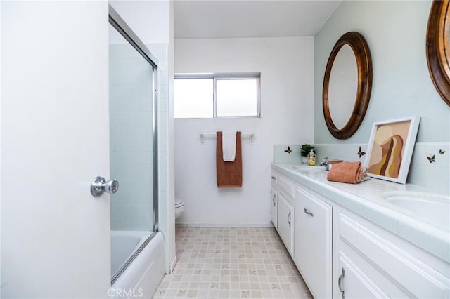 full bathroom featuring vanity, bath / shower combo with glass door, and toilet