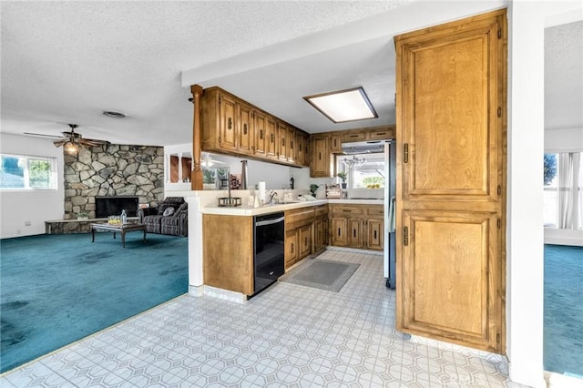 kitchen featuring dishwasher, a healthy amount of sunlight, light carpet, and a fireplace