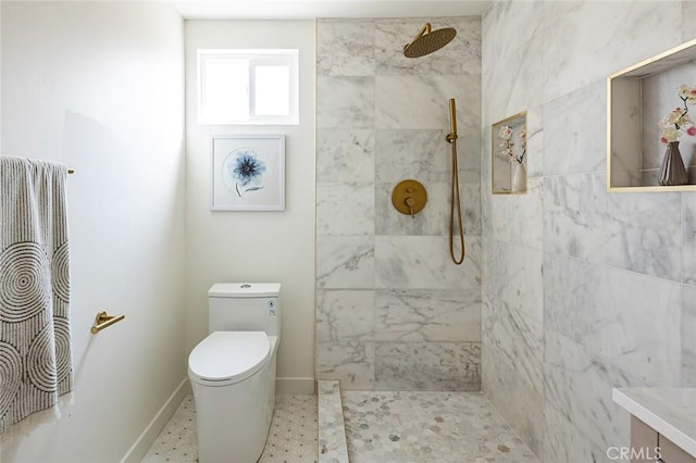 bathroom with tiled shower, vanity, and toilet