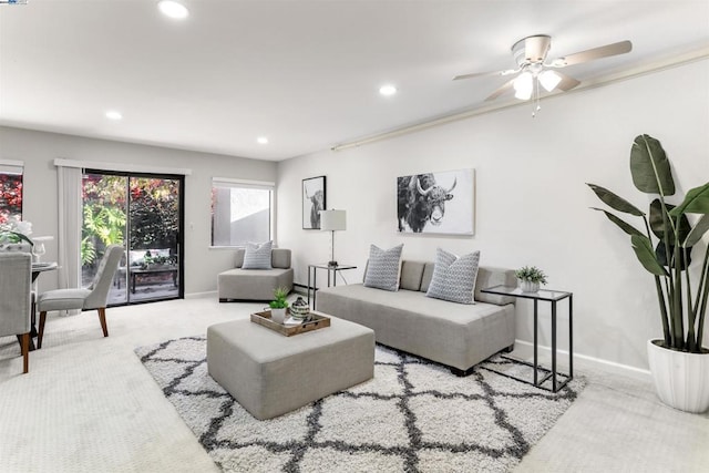 living room featuring ceiling fan, crown molding, and light colored carpet