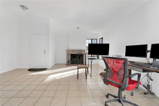 office area featuring lofted ceiling, light tile patterned floors, and a brick fireplace