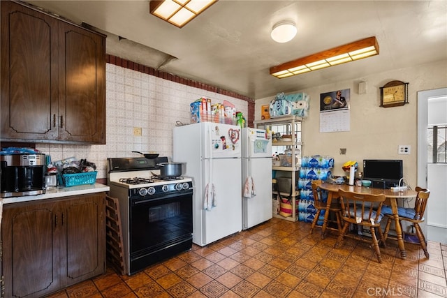 kitchen with gas stove, dark brown cabinetry, and white refrigerator