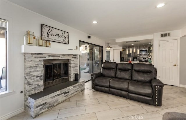 living room featuring a stone fireplace, plenty of natural light, and ceiling fan