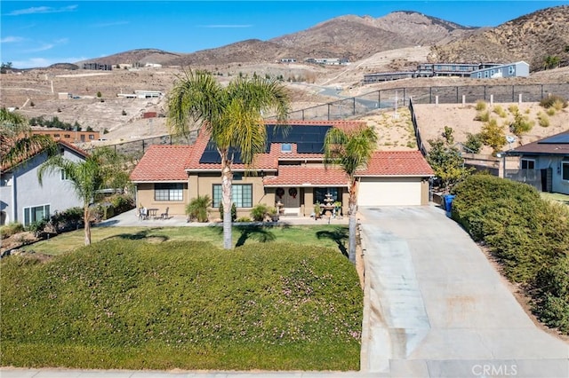 view of front of property with solar panels, a garage, and a mountain view