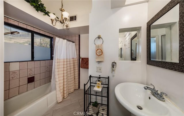 bathroom featuring an inviting chandelier, shower / tub combo with curtain, and sink