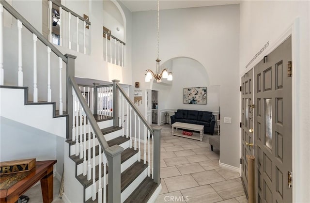 entrance foyer with a notable chandelier, light tile patterned flooring, and a high ceiling