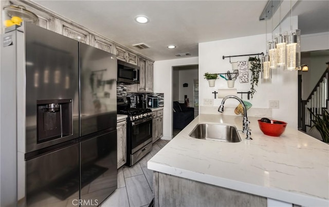 kitchen featuring light stone countertops, sink, kitchen peninsula, pendant lighting, and appliances with stainless steel finishes