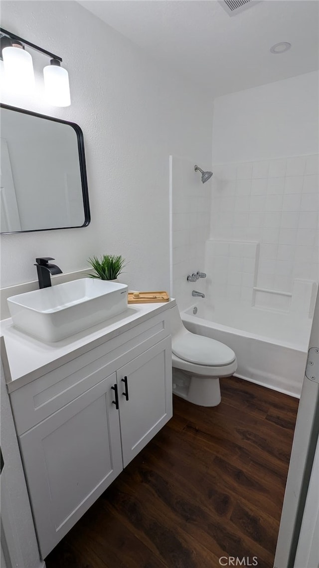 full bathroom with hardwood / wood-style floors, vanity, toilet, and  shower combination