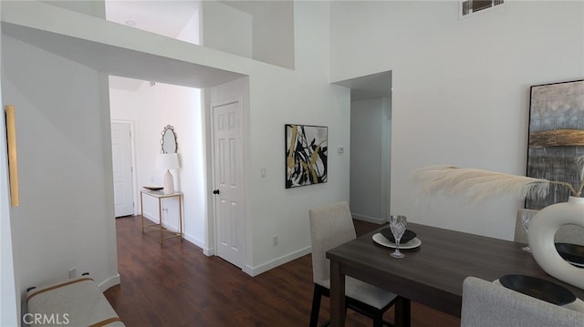 dining room with a high ceiling and dark wood-type flooring