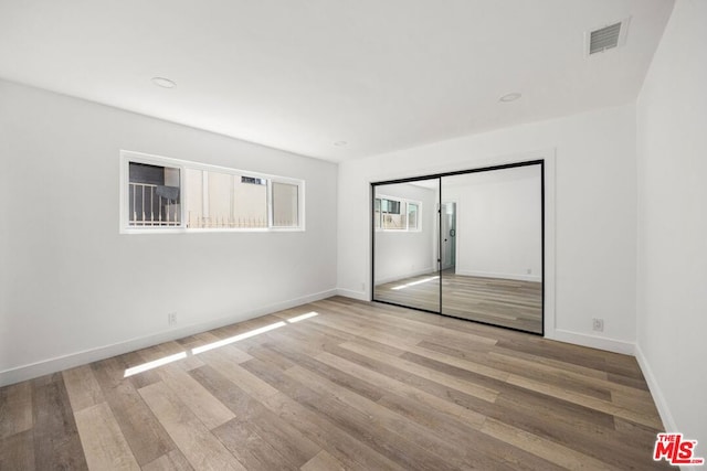 unfurnished bedroom with light wood-type flooring and a closet