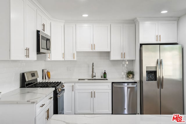 kitchen with white cabinets, sink, light stone countertops, and stainless steel appliances