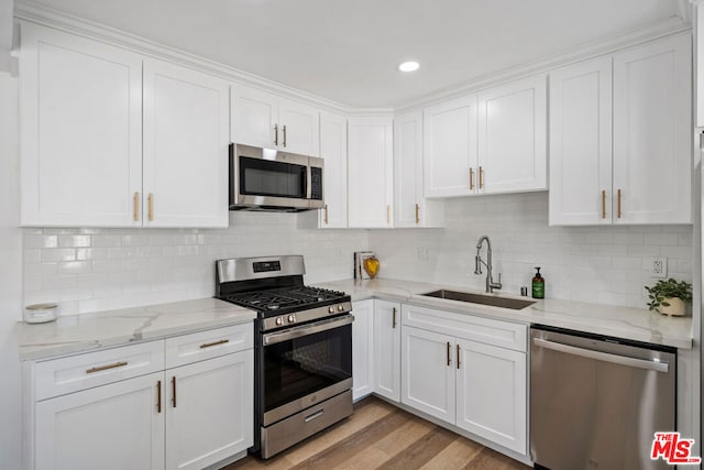 kitchen with sink, white cabinets, light hardwood / wood-style floors, and appliances with stainless steel finishes