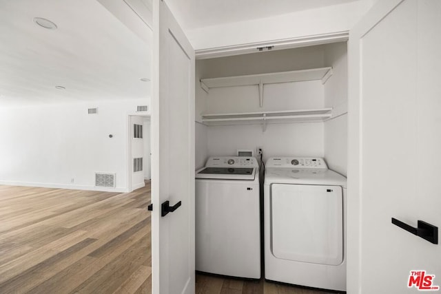 laundry room with washing machine and dryer and hardwood / wood-style flooring