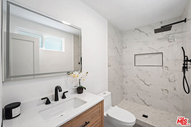 bathroom featuring a tile shower, vanity, and toilet