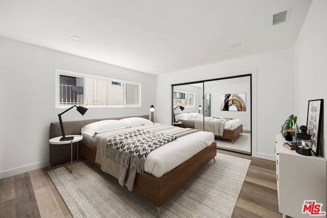 bedroom with dark hardwood / wood-style flooring and a closet