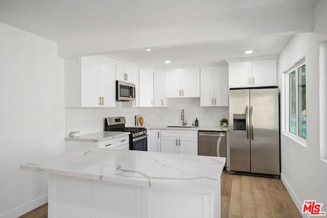 kitchen with white cabinets, appliances with stainless steel finishes, light hardwood / wood-style flooring, and sink