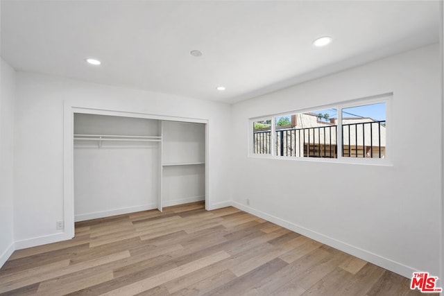 unfurnished bedroom with light wood-type flooring and a closet