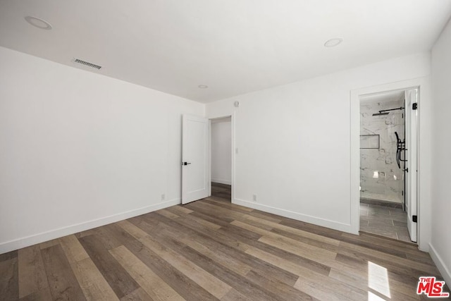 unfurnished bedroom featuring ensuite bath and hardwood / wood-style floors