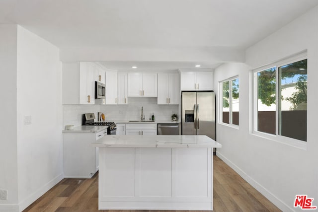 kitchen with white cabinets, decorative backsplash, hardwood / wood-style floors, and appliances with stainless steel finishes