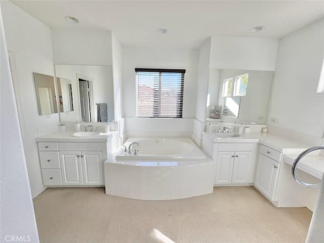 bathroom with vanity and tiled bath