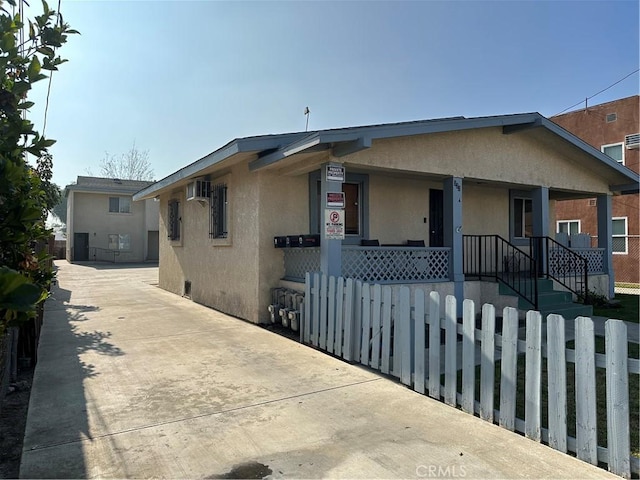 view of front facade with an AC wall unit and a porch