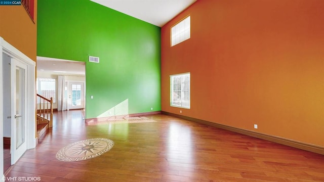 spare room with a healthy amount of sunlight, a high ceiling, and light hardwood / wood-style flooring